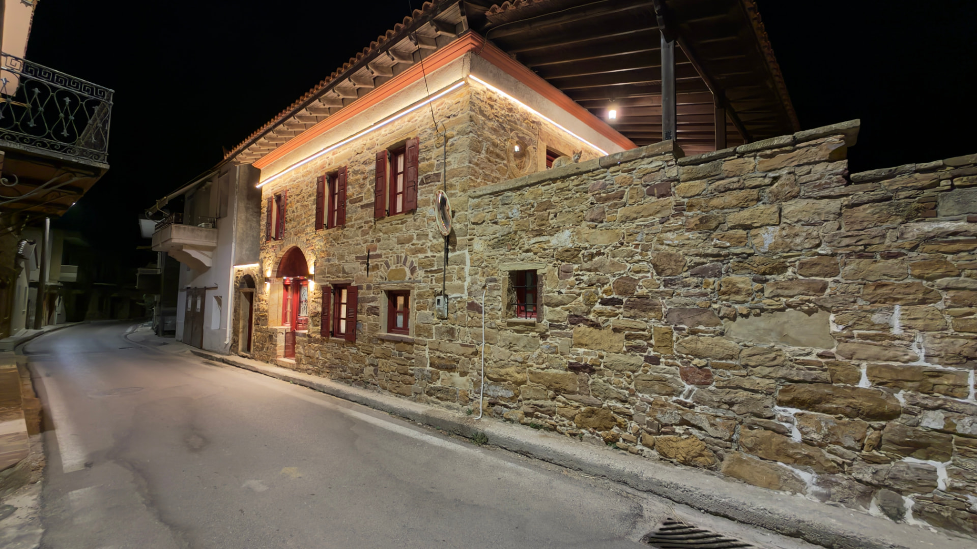 Exterior of the two-storey stone mansion, lit at night on a village street
