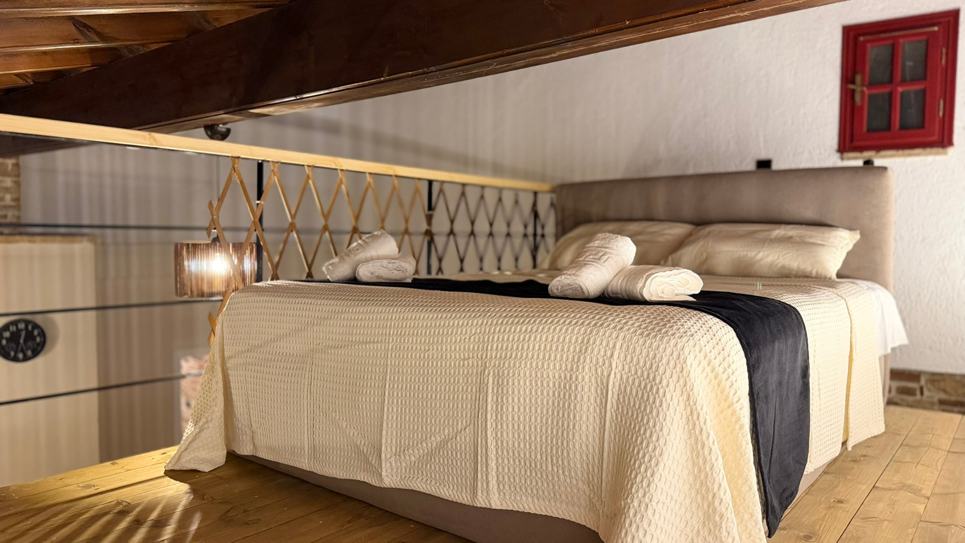Loft bed with timber beams, towels and a small red window